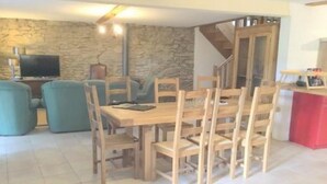 A dining area with a wooden table and chairs, a stone wall, and a staircase. - Exceptional setting, fresh air, peace and quiet, sleeps 12  (Anzat-le-Luguet)