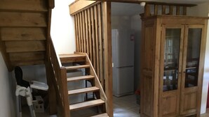 A wooden staircase leading to a second floor, a wooden cabinet with glass doors, and a white refrigerator in the background. - Exceptional setting, fresh air, peace and quiet, sleeps 12  (Anzat-le-Luguet)