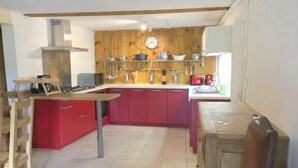 A kitchen with wooden cabinets, a stove, and a clock on the wall. - Exceptional setting, fresh air, peace and quiet, sleeps 12  (Anzat-le-Luguet)