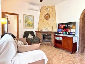 Uma sala de estar com lareira, televisão e uma parede de pedra.