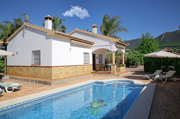 Relax by the serene pool surrounded by lush greenery and distant mountains.