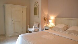 Ein Schlafzimmer mit einem großen Bett, einem Sessel, einem Kleiderschrank und einem Nachttisch mit einer Lampe.