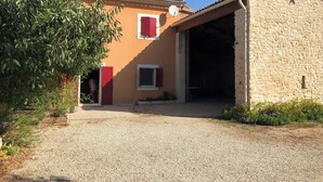 Un bâtiment de style rustique, avec une allée en gravier, un porche abrité et un petit jardin.