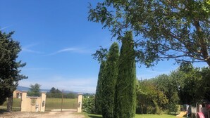 Un camino de grava conduce a una entrada con portón, bajo un cielo despejado.