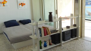 Ein modernes Schlafzimmer mit einem Bett, Bücherregalen und Blick ins Freie.