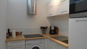 Eine kleine Küche mit Waschmaschine, Kaffeemaschine und Mikrowelle.