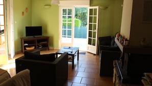 Una sala de estar con televisión, sofá y mesa de comedor.