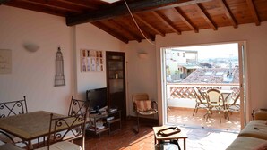 A cozy living room with a wooden ceiling, a TV, and a balcony with chairs. - Located in old Antibes, 2 steps from shops, sleeps 2 to 3 (Antibes)