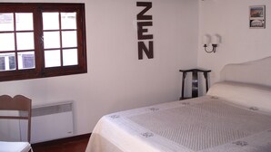 A bedroom with a bed, a window, a wall-mounted sign, a chair, a bedside table, and a wall-mounted lamp. - Located in old Antibes, 2 steps from shops, sleeps 2 to 3 (Antibes)
