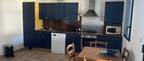 A compact kitchen with dark blue cabinets, a wooden dining table, and a microwave.