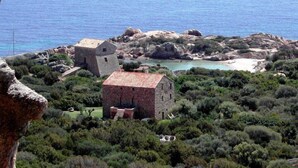 Un borgo costiero con edifici in pietra, una spiaggia e terreno roccioso.