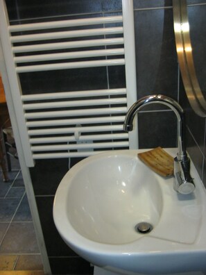 Une salle de bain avec un lavabo blanc, un robinet chromé et un porte-savon en bois.