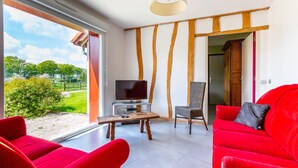 A modern living room with a large window, a flat-screen TV, a wooden coffee table, and red upholstered furniture. - Farm cottage, games room and jacuzzi and sauna option, near Touquet beach (Pas-de-Calais)