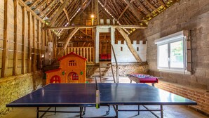 A room with two ping pong tables, a small model house, and a window with a view of greenery. - Farm cottage, games room and jacuzzi and sauna option, near Touquet beach (Pas-de-Calais)
