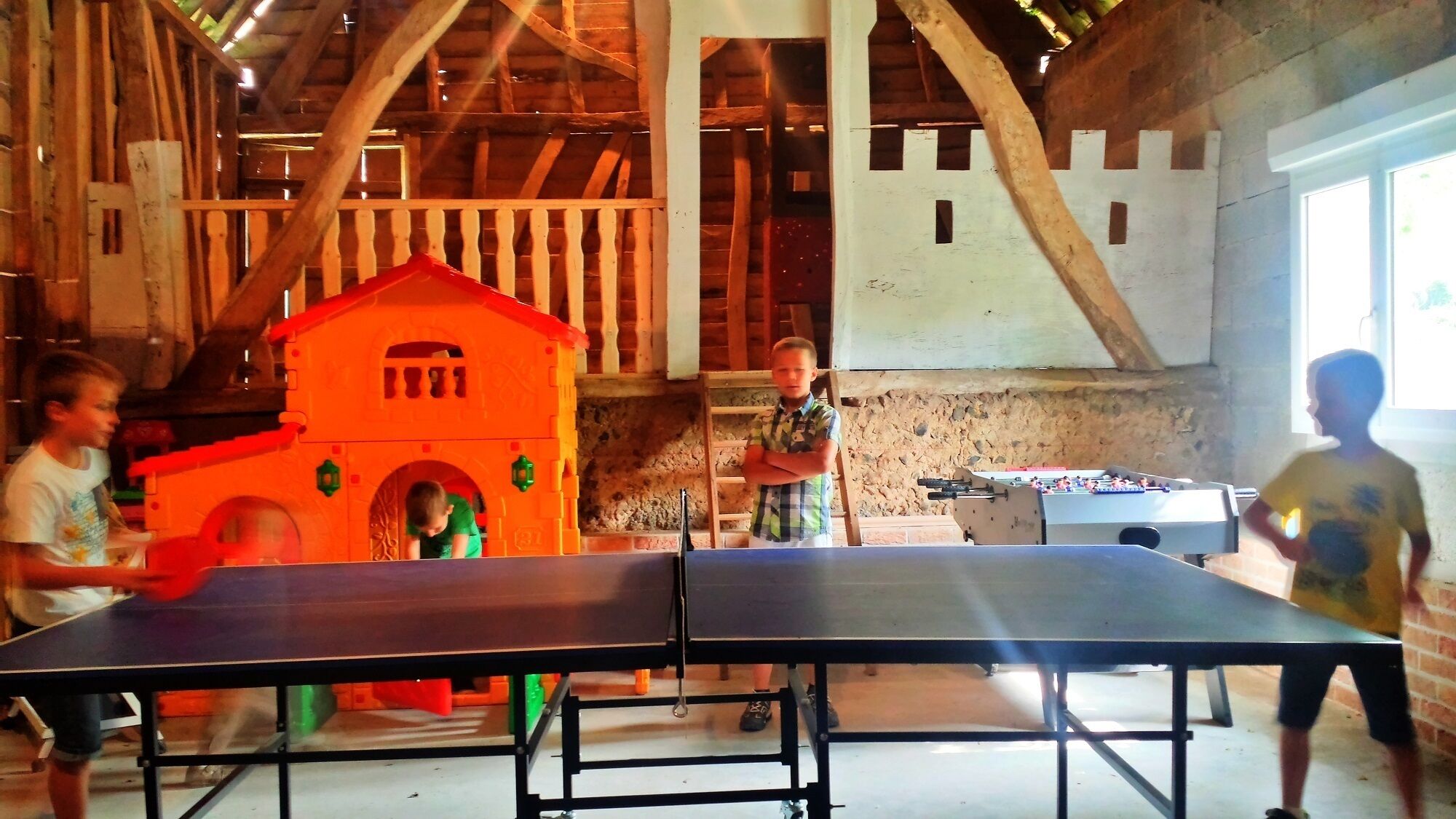 Um quarto com mesa de pingue-pongue, casinha de brincar e mesa de futebol de mesa.