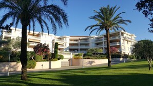 A multi-story hotel with balconies, surrounded by well-maintained lawns and palm trees. - SAINT-RAPHAEL COTE D'AZUR Grand F2 pour 5p Piscine Au calme vue mer Tout à pied (Saint-Raphaël)