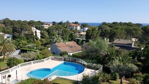A residential area with a swimming pool, surrounded by lush greenery and houses with Mediterranean architecture. - SAINT-RAPHAEL COTE D'AZUR Grand F2 pour 5p Piscine Au calme vue mer Tout à pied (Saint-Raphaël)