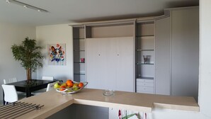 A modern kitchen with a dining table, a fruit bowl, and a potted plant. - SAINT-RAPHAEL COTE D'AZUR Grand F2 pour 5p Piscine Au calme vue mer Tout à pied (Saint-Raphaël)