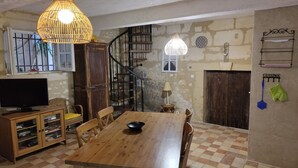 A dining area with a wooden table, chairs, a television, and a staircase leading to an upper level.