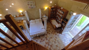 A cozy room with a wooden bed, a bookshelf, and a small window.