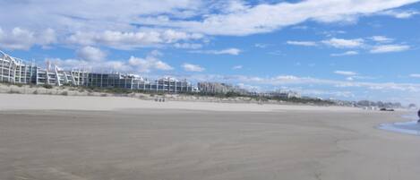 Een strand met een modern gebouwcomplex op de achtergrond.