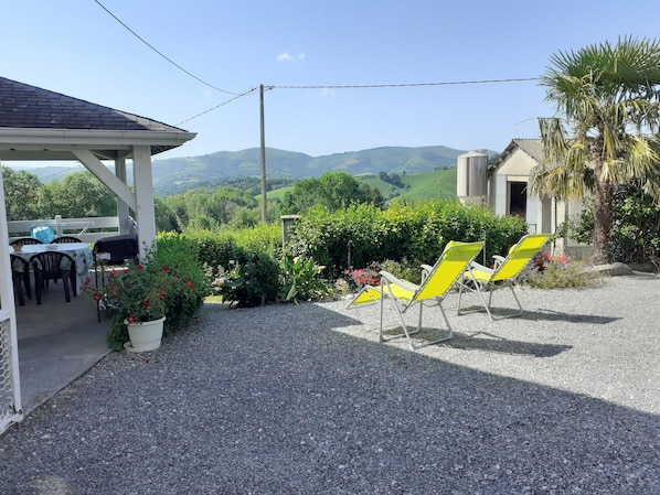A patio with outdoor seating, a covered area, and a view of rolling hills.