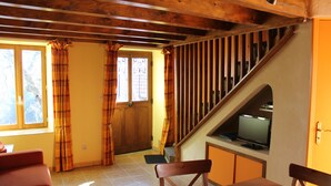 Una sala de estar acogedora con una escalera de madera, un televisor y un sofá.