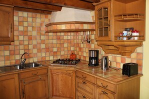 A kitchen with wooden cabinets, a tiled backsplash, and various appliances including a stove, coffee maker, and toaster.