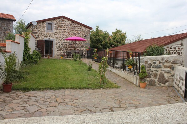 A stone house with a tiled roof, a paved courtyard, and a small garden with potted plants. - 45 m2 self-catering cottage for 2 people in the Parc des Volcans d'Auvergne (SAINT - DIERY)