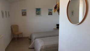 A bedroom with two beds, a chair, a small table, and a wall-mounted mirror. -  Between Ventoux and Luberon *** (Aurel)