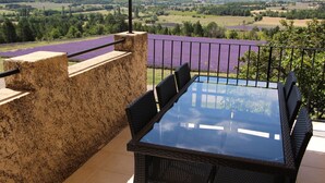 A balcony with a glass table and chairs, overlooking a lavender field and distant hills. -  Between Ventoux and Luberon *** (Aurel)