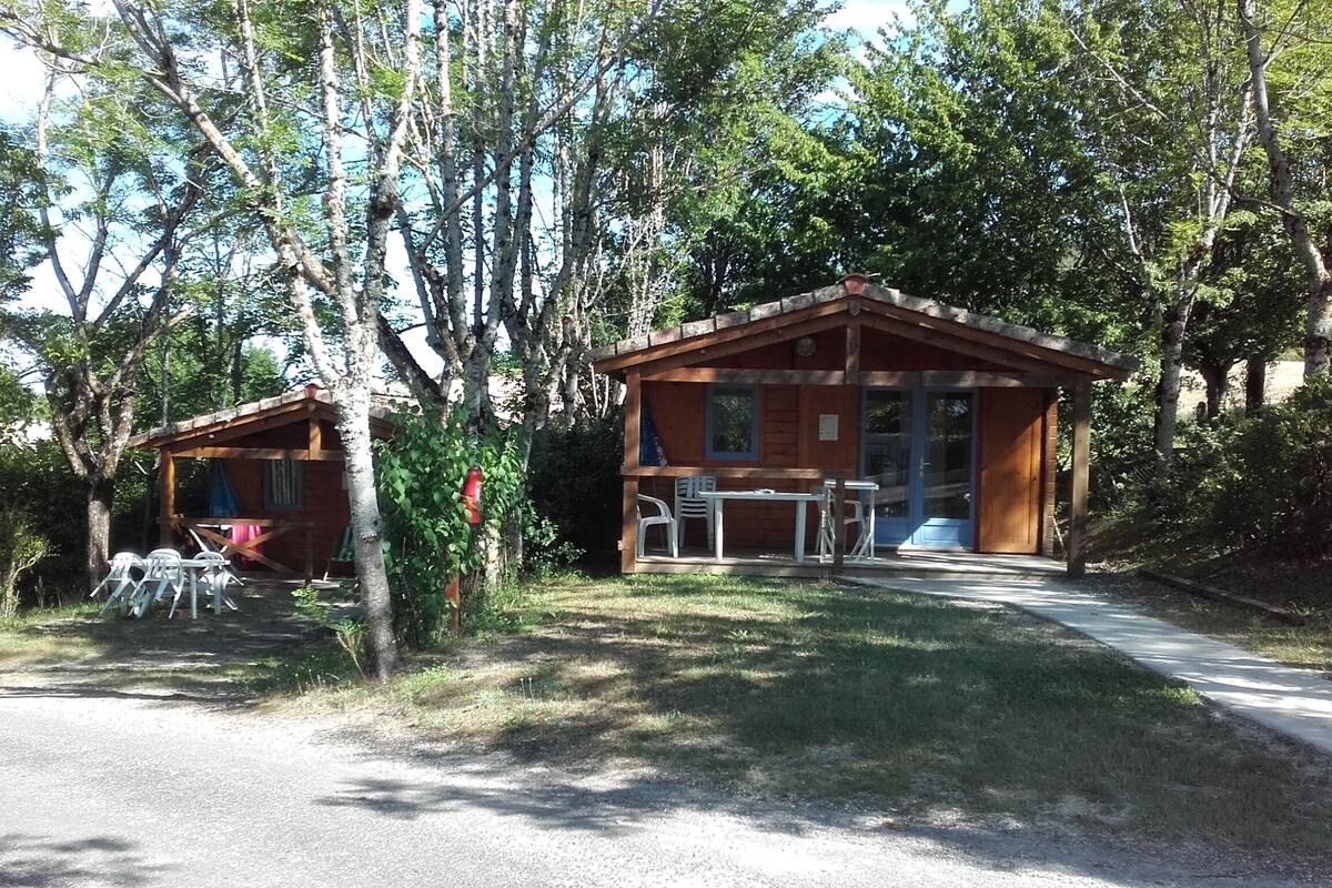 Duas cabanas de madeira com varandas, rodeadas por árvores.