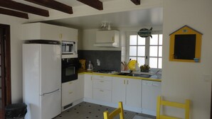 Cuina amb armaris blancs, fogó negre i taulell groc.