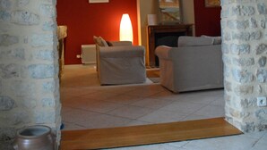 A room with stone walls, a wooden ceiling, a fireplace, and a sofa. - House 20 mn from the beaches, 7 people, neat decoration, fully equipped (Crouay)