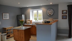 A modern kitchen with wooden cabinets, a central island, and a window with a view. - House 20 mn from the beaches, 7 people, neat decoration, fully equipped (Crouay)
