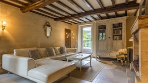 A cozy living room with a white sofa, a coffee table, and a bookshelf. - 18th century stone house in the heart of the D-Day landing beaches  (Ver-Sur-Mer)