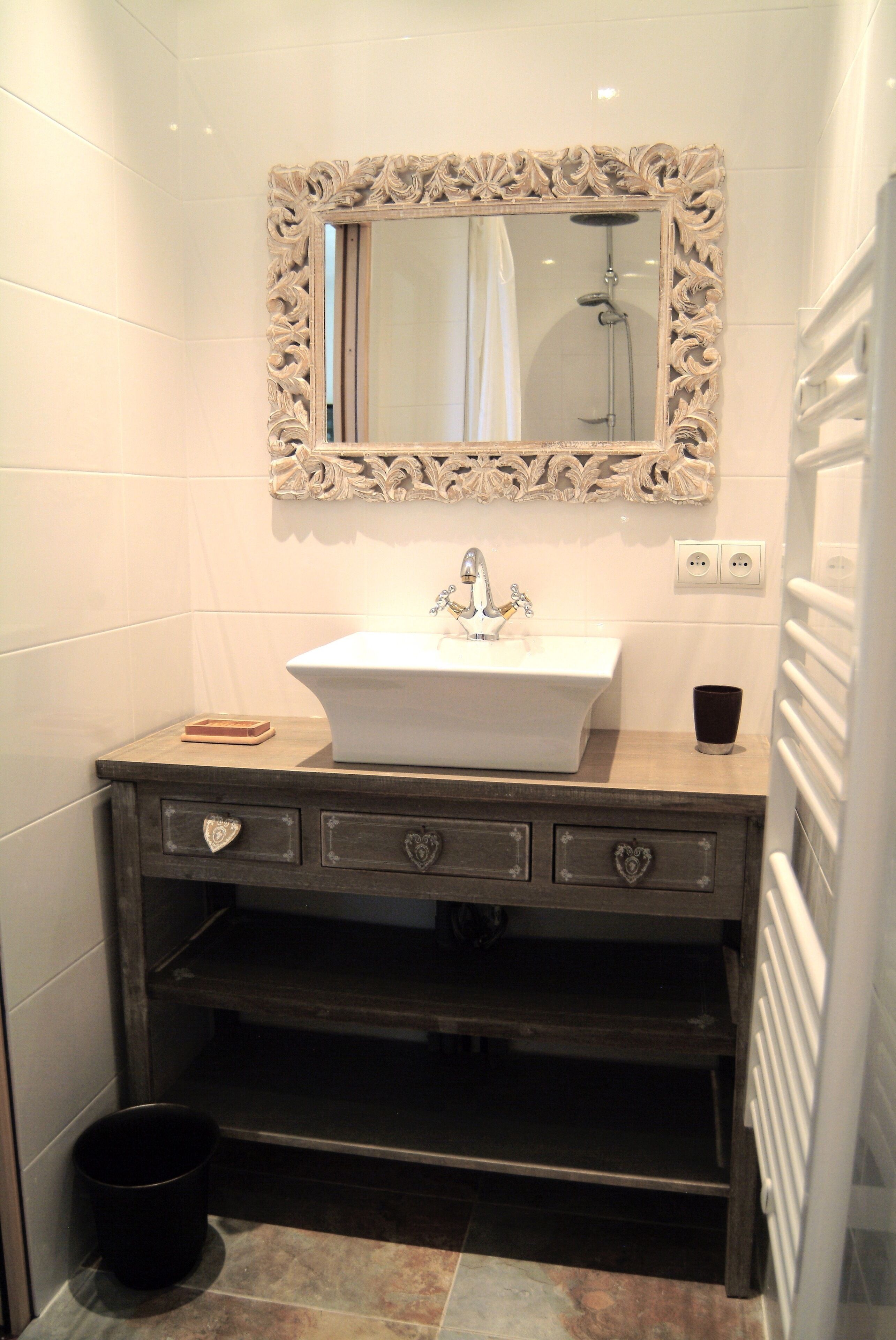 A bathroom with a white sink, ornate mirror, and dark wooden vanity with heart-shaped handles.