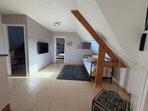 A room with a sloped ceiling, a bed, a desk, a television, and a staircase.