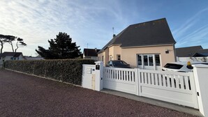 A residential building with a gated driveway, a carport, and a well-maintained hedge.