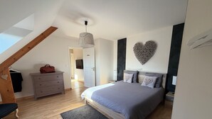 A bedroom with a bed, dresser, and a heart-shaped wall decoration.