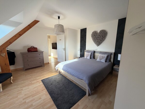 A bedroom with a bed, dresser, and a heart-shaped wall decoration.
