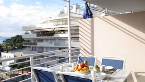Een balkon met een tafel, gedekt voor het ontbijt, met fruit en theekopjes.