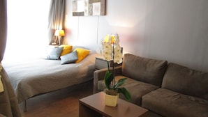 Een hotelkamer met een bed, een bank, een tafeltje en een kamerplant.