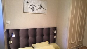 Une chambre à coucher avec une tête de lit capitonnée, deux lampes de chevet et un lit recouvert d’une courtepointe matelassée.