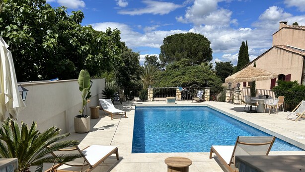 Una piscina con sillas de descanso y un muro de piedra.