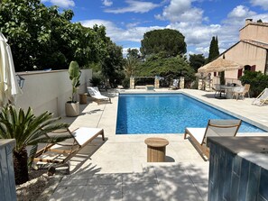 A swimming pool with lounge chairs and a stone wall.