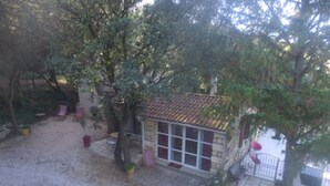 Pequeño edificio de piedra con techo de tejas, rodeado de árboles y un camino de entrada de grava.
