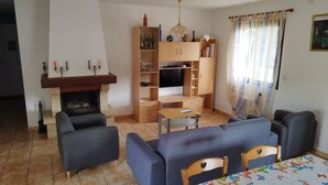 Un salon avec une cheminée, un canapé, une télévision et une table à manger.