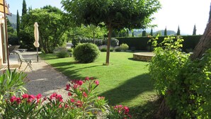 Ein gepflegter Garten mit Rasen, einer Steinsitzbank und einer Pergola.