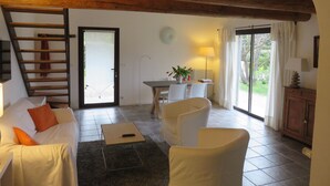 Ein gemütliches Wohnzimmer mit Holzbalkendecke, einer Couch, einem Couchtisch und einem Essbereich mit Stühlen und einem Tisch.